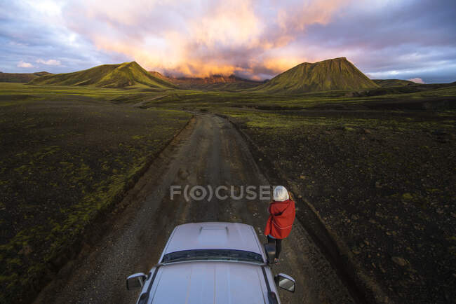 Fotógrafo tirando fotos do pôr do sol nas montanhas ao lado do carro — Fotografia de Stock