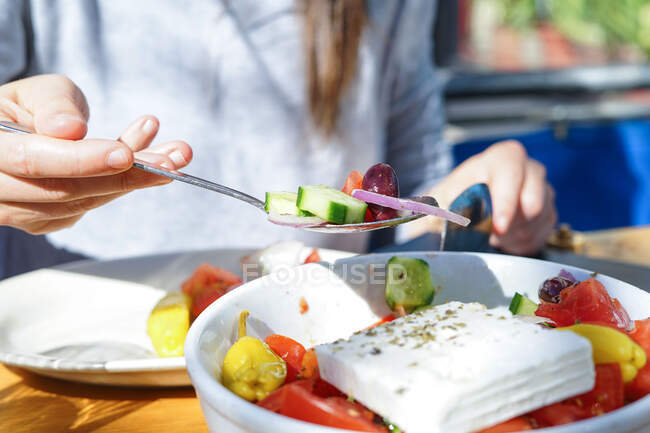 Un cucchiaio di insalata mediterranea, tenuto da una donna — Foto stock