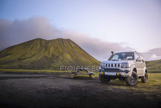 4x4 parked next to picnic table in front of mountain next to river — Stock Photo