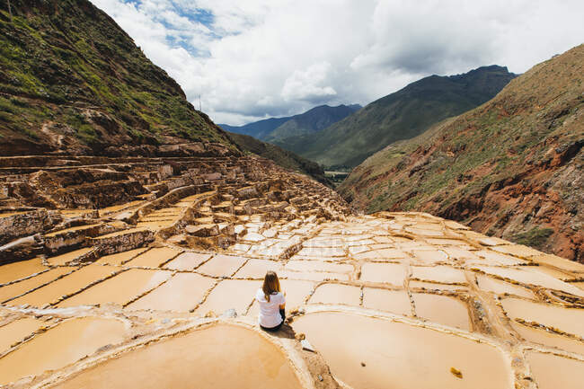 Молодая женщина сидит рядом со знаменитыми соляными шахтами в Перу — стоковое фото