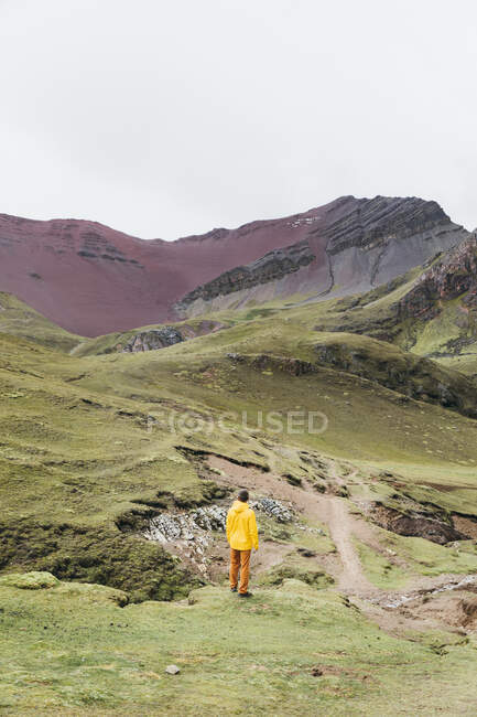 Un uomo in giacca gialla è in piedi su una collina in Perù — Foto stock