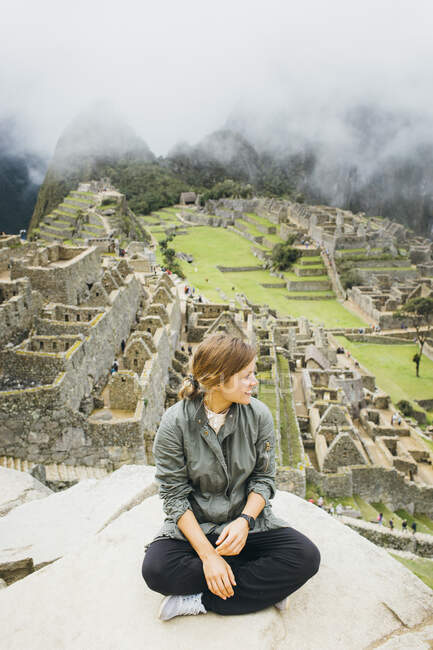A young woman is sitting near ruins of Machu Picchu, Peru — Stock Photo