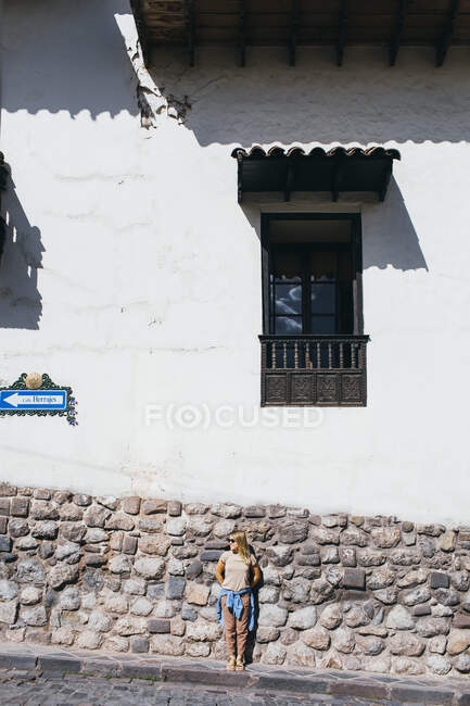 A young woman is standing near a white wall in Cusco, Peru — Stock Photo