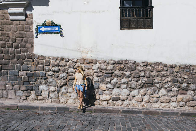 Молодая женщина стоит возле белой стены в Куско, Перу — стоковое фото