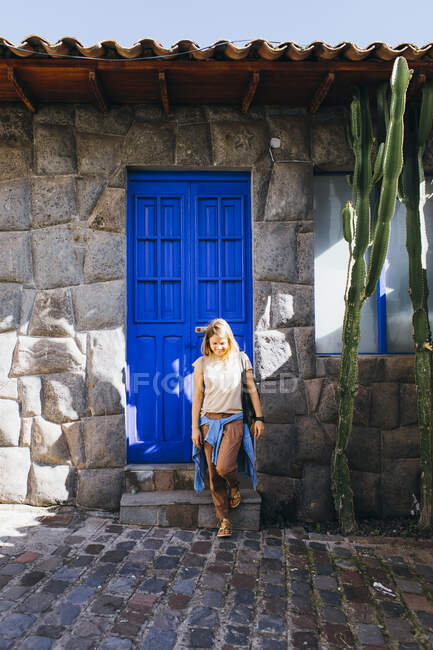 Eine junge Frau steht in der Nähe einer blauen alten Tür in Cusco, Peru — Stockfoto