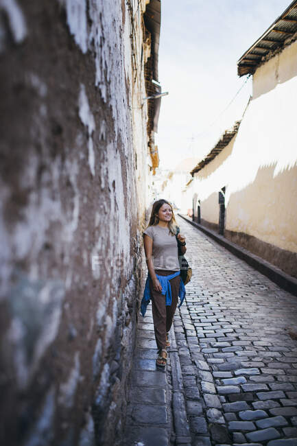 Una giovane donna è in piedi vicino a un vecchio muro a Cusco, Perù — Foto stock