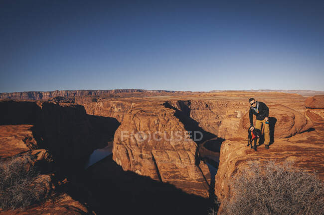 A man with a dog is standing near Horseshoe Bend, Arizona — Stock Photo