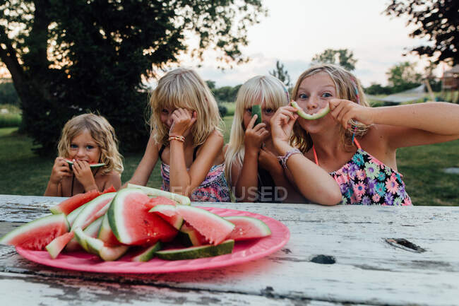 Niños pequeños divirtiéndose comiendo sandía afuera riendo en el verano - foto de stock