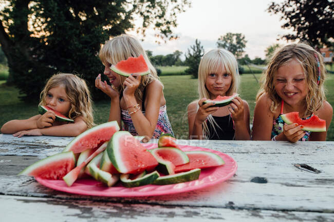 Frères et sœurs qui s'amusent à manger de la pastèque dehors en été — Photo de stock