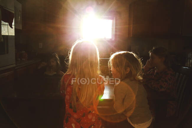 Children eating breakfast at table in morning sunflare — Stock Photo