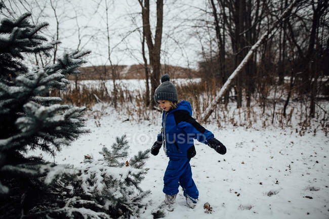 Маленький хлопчик у сніжному костюмі грає у снігу взимку — стокове фото