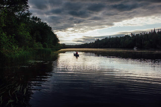 Hombre navegando en canoa al amanecer río abajo en el norte de Canadá - foto de stock