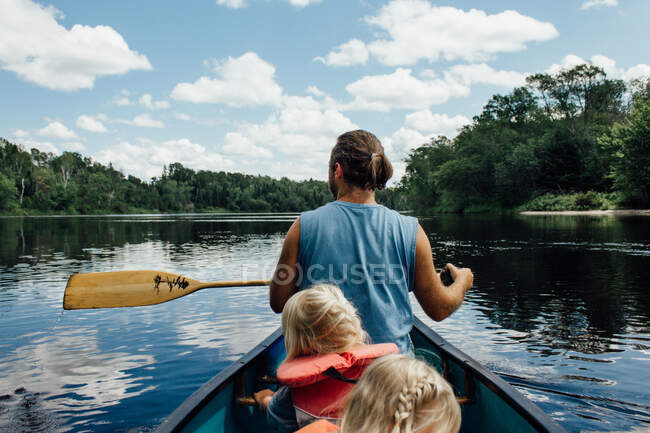Homem canoagem com crianças pequenas rio abaixo no norte do ontário — Fotografia de Stock