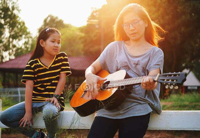 Mother show to her daughter how to play the guitar — Stock Photo