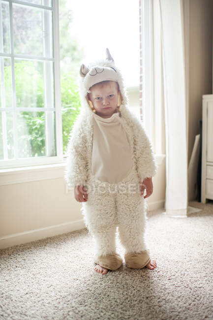 Menino vestido com traje de lama fazendo um rosto rabugento em pé pela janela — Fotografia de Stock