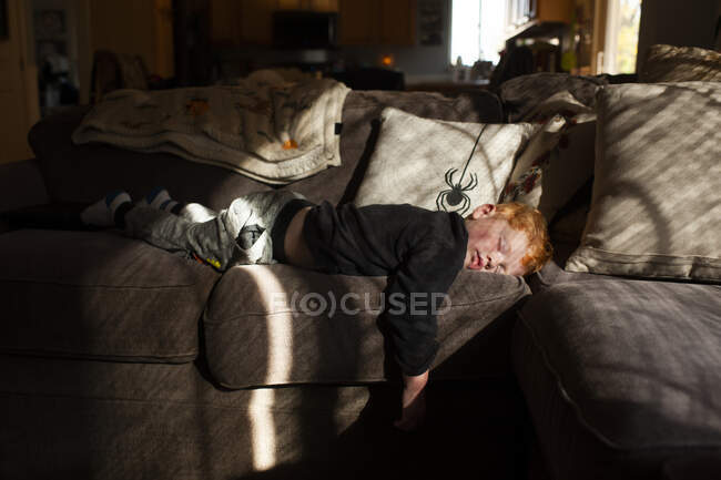 Menino criança dormindo de barriga no sofá em casa em luz bonita — Fotografia de Stock