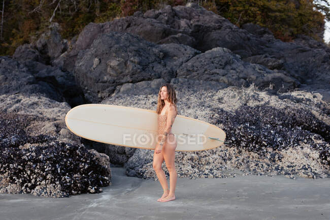 Beautiful, fit woman with surfboard on beach in Tofino — Stock Photo