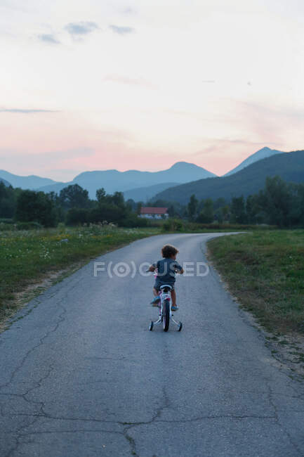 Petit garçon chevauchant un vélo dans les montagnes — Photo de stock