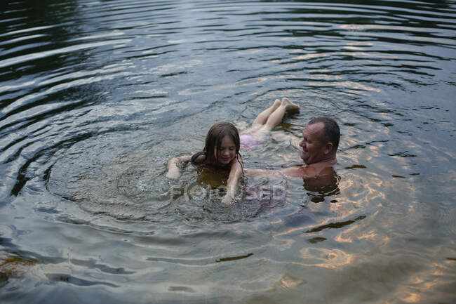 Una niña aprendiendo a nadar al atardecer - foto de stock