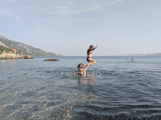 Duas criançasJogando e pulando no mar — Fotografia de Stock