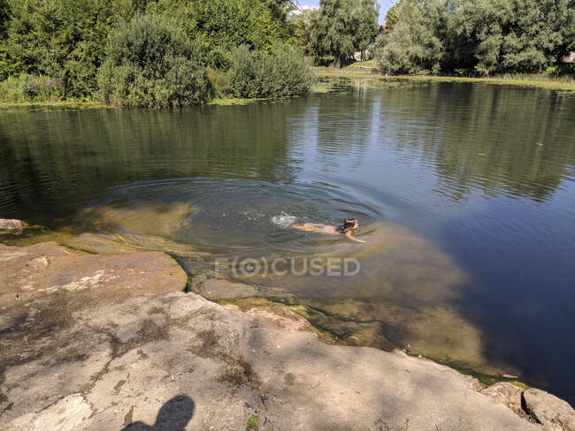 Kleines Mädchen schwimmt im Teich — Stockfoto