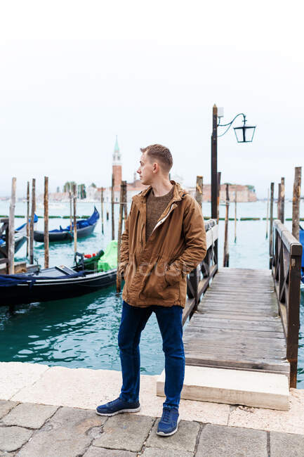 Молодий блондин у коричневій куртці посеред вулиць Венеції. — стокове фото