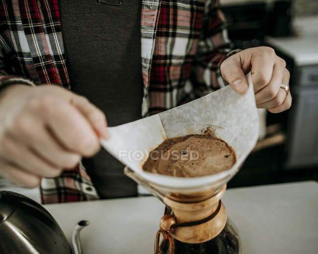 Man with wedding ring and flannel steadies pour over coffee filter — Stock Photo