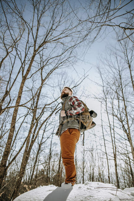 Человек с бородой носит фланелевые стойки на покрытой снегом скале — стоковое фото