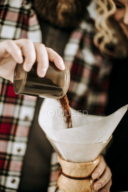 Man with flannel pours coffee grounds into pour over filter — Stock Photo