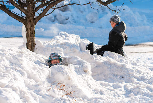 Zwei Jungen bauen an einem sonnigen Wintertag Schneeforts mit einer Schaufel — Stockfoto