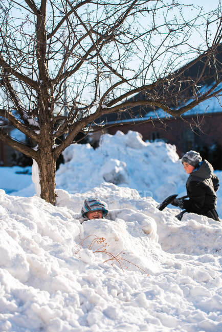 Двоє хлопців будують снігові форти з лопатою в сонячний зимовий день. — стокове фото