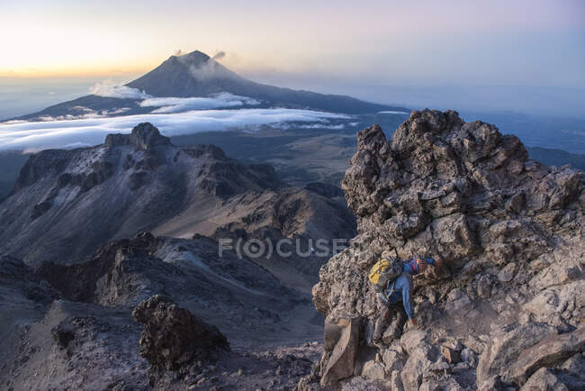 Un hombre sube a la cima de una montaña - foto de stock