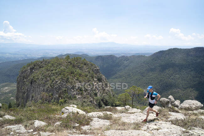 Um homem de meia idade correndo em uma trilha rochosa cênica. — Fotografia de Stock