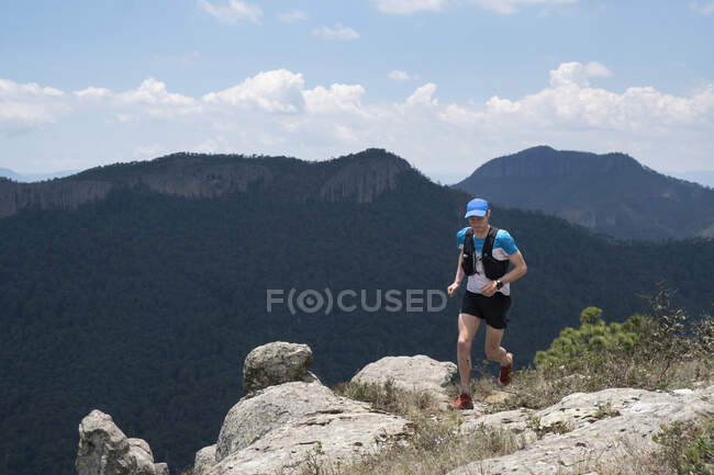 Um homem correndo em um terreno rochoso em uma área de montanha no México — Fotografia de Stock