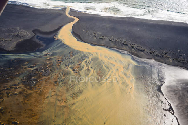 Aerial view of braided orange river flowing into ocean in southern Iceland — Stock Photo