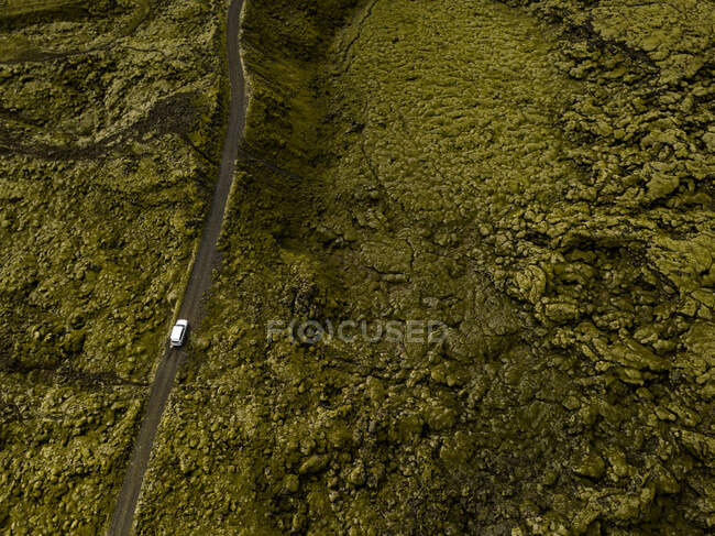 Aerial view of car driving through moss covered lava rocks — Stock Photo