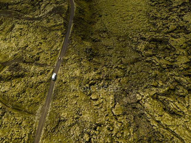 Vue aérienne de la voiture conduisant à travers les roches de lave couvertes de mousse — Photo de stock