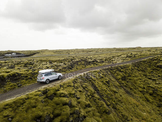 Vista aérea do carro dirigindo através de rochas de lava cobertas de musgo — Fotografia de Stock