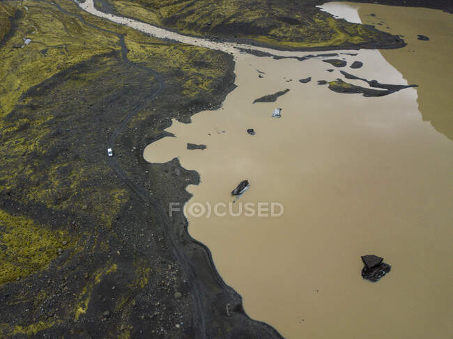 Aerial of car driving on gravel road near glacial lake — Stock Photo