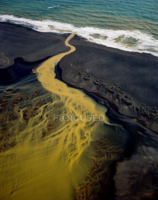 Luftaufnahme des geflochtenen orangefarbenen Flusses, der im Südosten in den Ozean fließt — Stockfoto