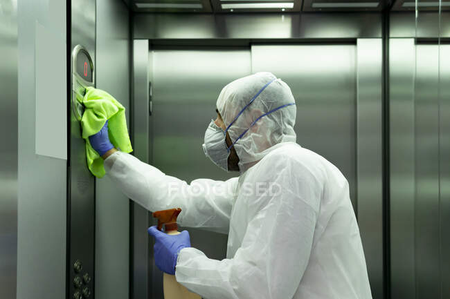 Coronavirus. Worker disinfecting hospital elevator to avoid contagion. — Stock Photo