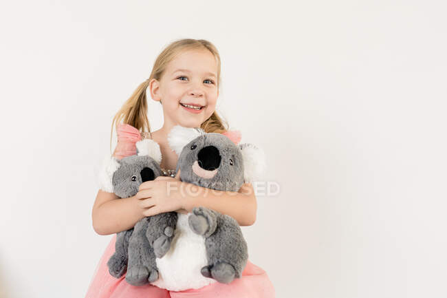 Graziosa bionda bambina abbracciare koala animali imbalsamati al chiuso — Foto stock