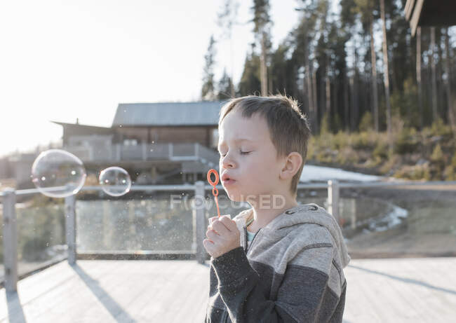 Menino soprando bolhas em sua varanda em casa na Suécia — Fotografia de Stock