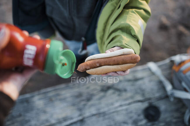 Bambino in possesso di un hot dog in attesa di ketchup durante il campeggio — Foto stock