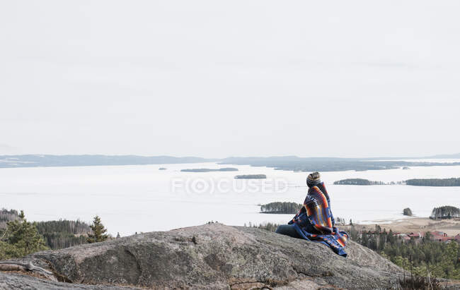 Mujer sentada en una roca mirando una hermosa vista de Suecia - foto de stock
