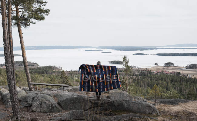 Жінка тримає ковдру, що стоїть на скелі з красивим видом — стокове фото