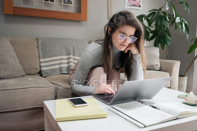 Mujer joven con portátil y tarjeta de crédito en el sofá en casa - foto de stock