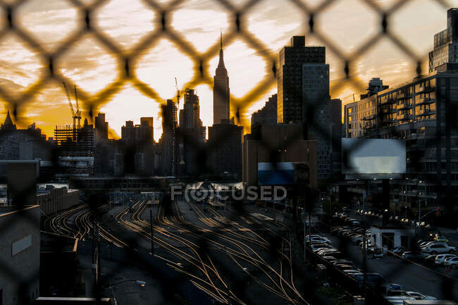 Trilhas de trem vazias brilhando por trás de uma cerca ao pôr do sol em Nova York. — Fotografia de Stock