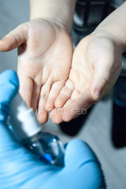 Médico trata las manos de los niños con un antiséptico - foto de stock