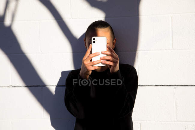 Frau schaut mit Baumschatten auf Handy — Stockfoto